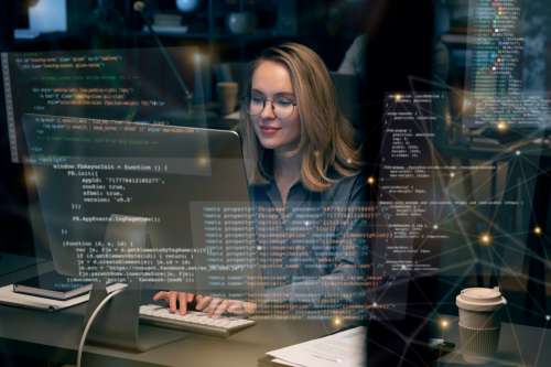 Mujer programadora escribiendo código en una computadora en un entorno de oficina moderna, con múltiples líneas de c&